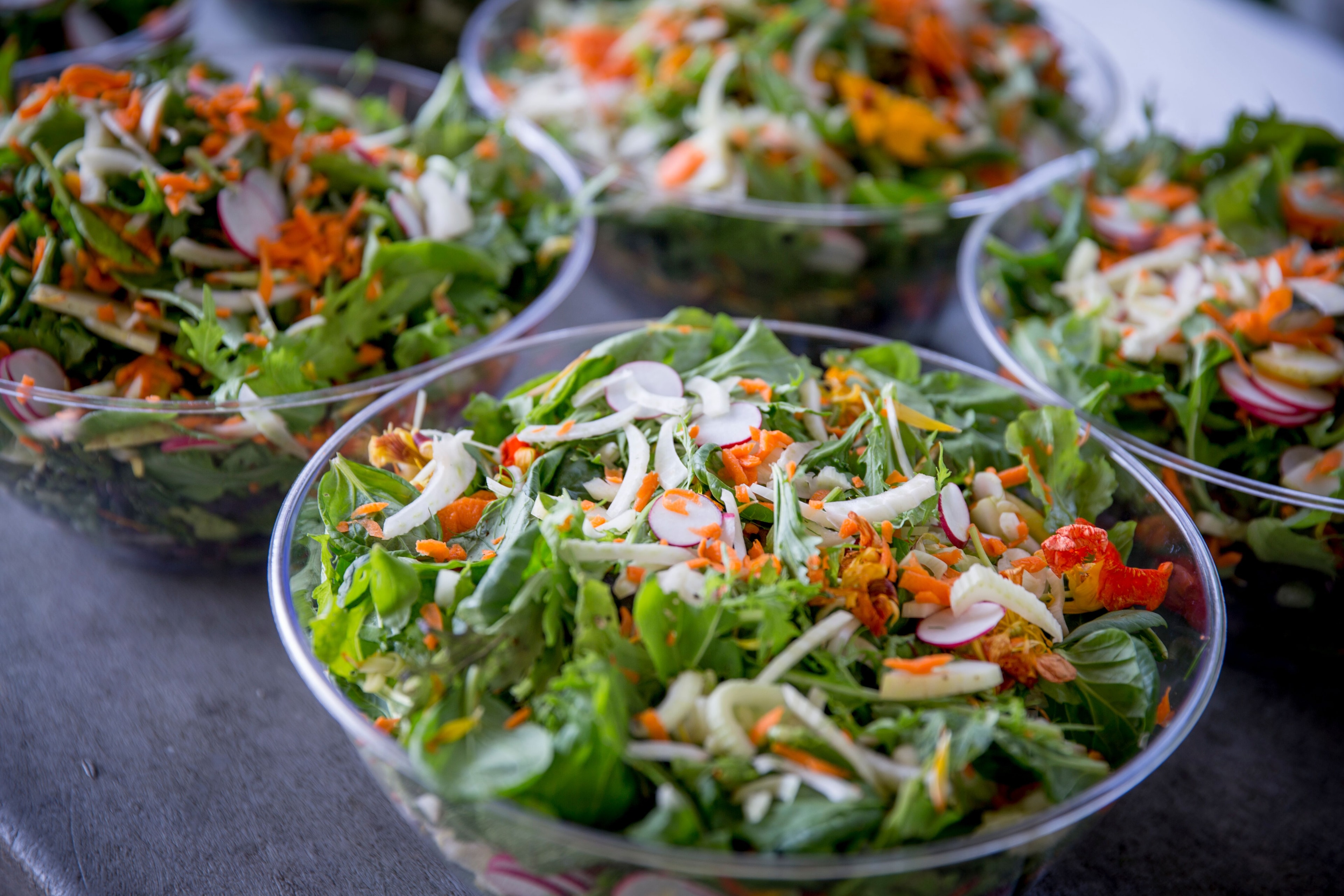 Fresh garden salads in clear bowls with edible flowers