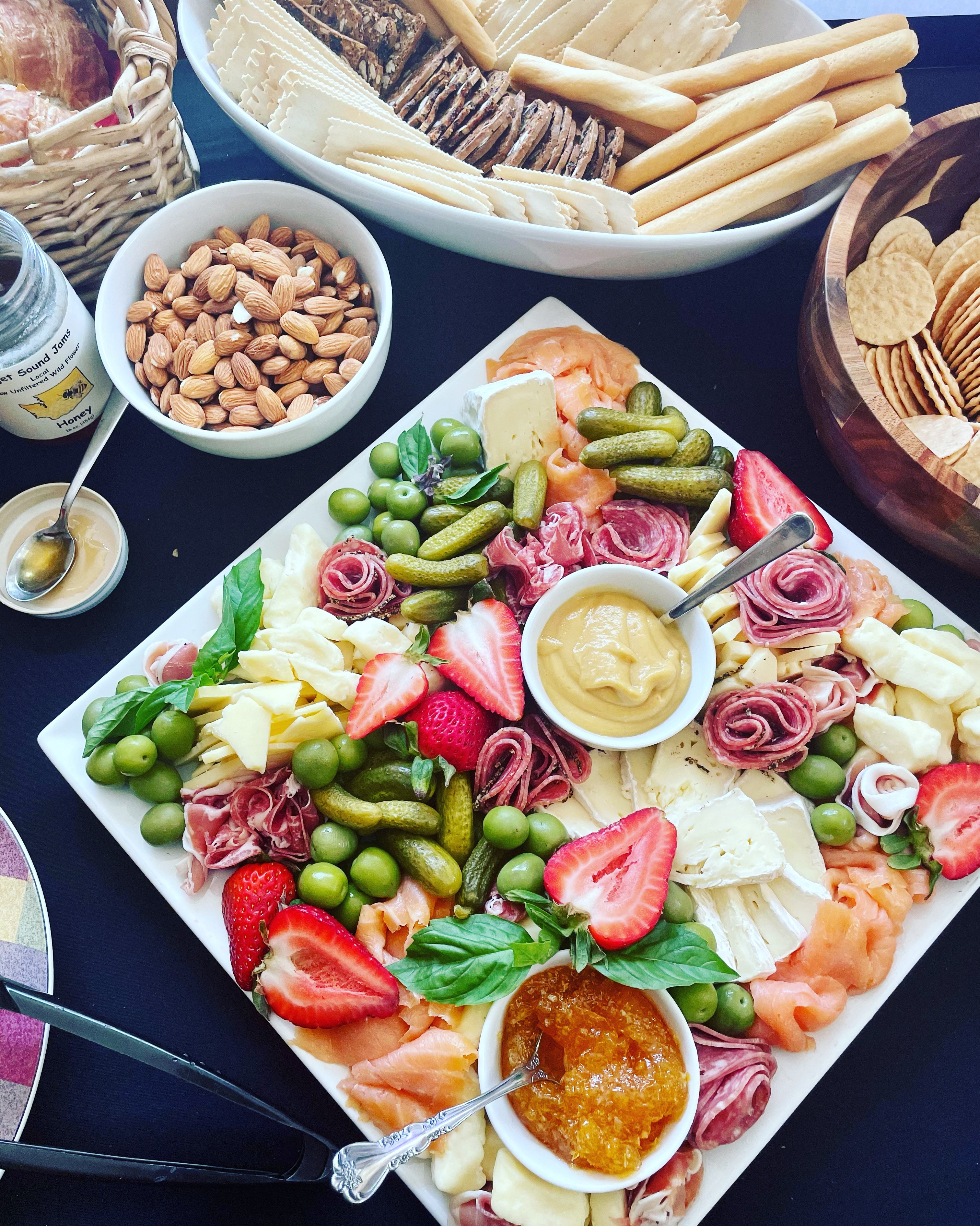 Charcuterie board with salami brie strawberries olives and jam